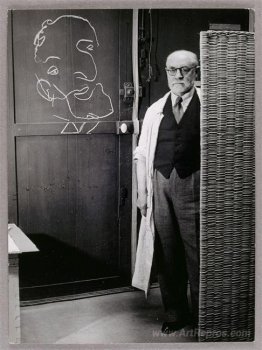 Henri Matisse standing against a screen and drawing with chalk